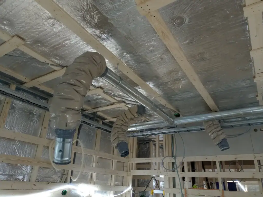Installasjon av ventilasjonsrør og isolasjon i innemiljøbygg.