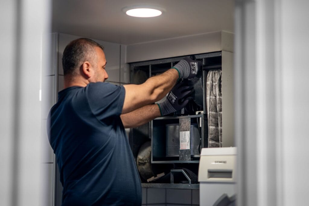 Tekniker utfører service og vedlikehold av ventilasjonsanlegg i et moderne bygg.